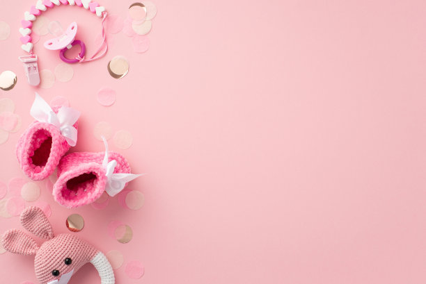 小配件的概念。顶视图照片的安抚链粉红色靴子针织兔子摇铃玩具和闪亮的纸屑孤立粉彩粉红色的背景与copyspace图片下载