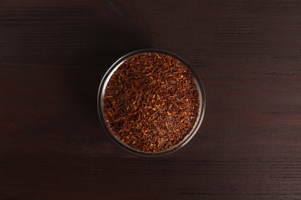 干燥的鲁伊波士树叶在玻璃碗在木桌子上，俯视图图片下载