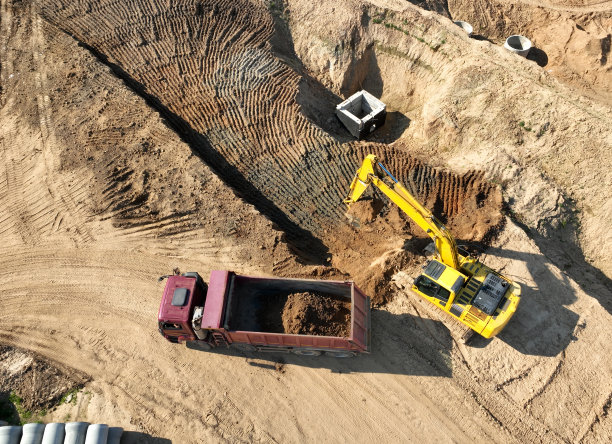 挖掘机将沙子装入自卸卡车。建筑工地的土方工程。图片下载