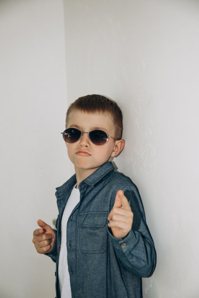 一个穿着衬衫的男孩站在那里，从墨镜下向外张望图片下载