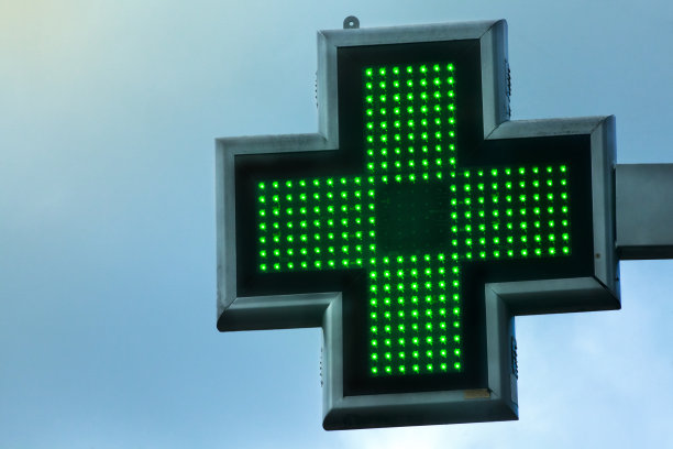 药房绿色十字标志附建筑立面，蓝天背景。图片下载