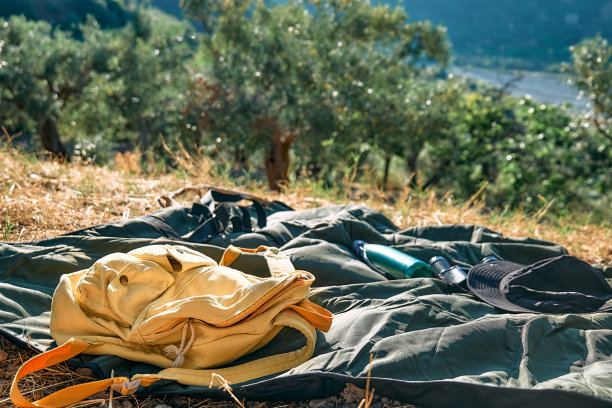 旅游的背景。黄色背包，帽子和望远镜放在野餐毯上，可以看到山景。积极的人，远足，健康的生活方式和和谐的理念。与自然统一。图片下载