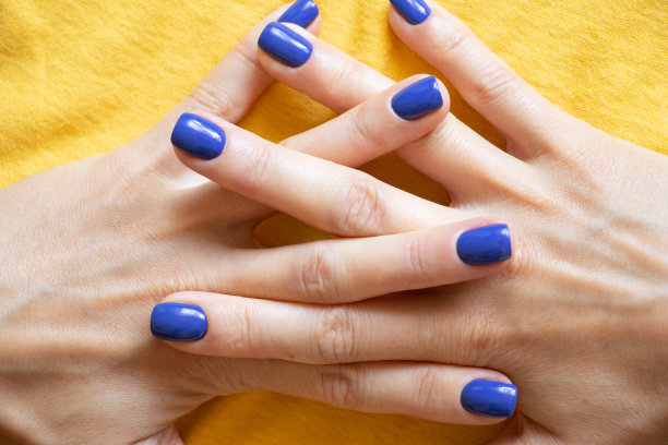 女孩的手指上涂着蓝色的指甲油，背景是黄色的乌克兰国旗，女孩的指甲上涂着凝胶指甲油图片下载