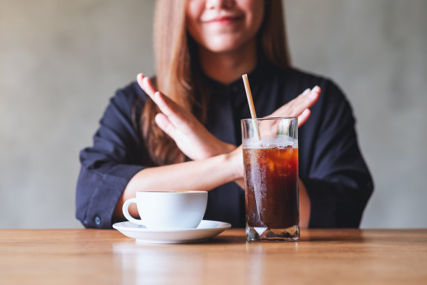 一名年轻女子双手交叉示意拒绝喝冰咖啡和热咖啡图片下载