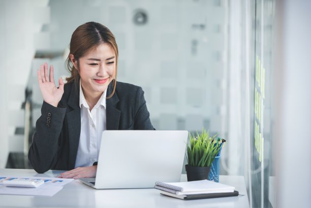 一个幸福和迷人的亚洲女人的肖像。为现代办公室的平板电脑提供视频会议功能。做一份会计分析报告。房地产投资信息展示概念图片下载