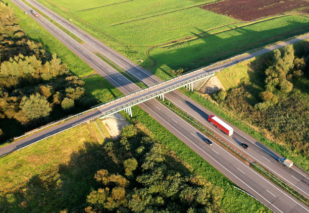 公路沿绿油油的原野设有公路桥和交通交汇处，从空中俯瞰。图片下载