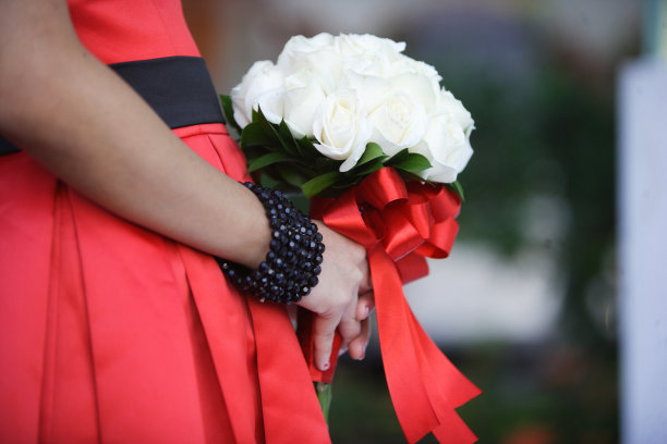 身穿红色连衣裙的女子手持一束白色玫瑰图片下载