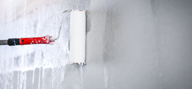 滚筒刷墙，工人用白色滚筒在干净的墙面上刷墙。图片下载