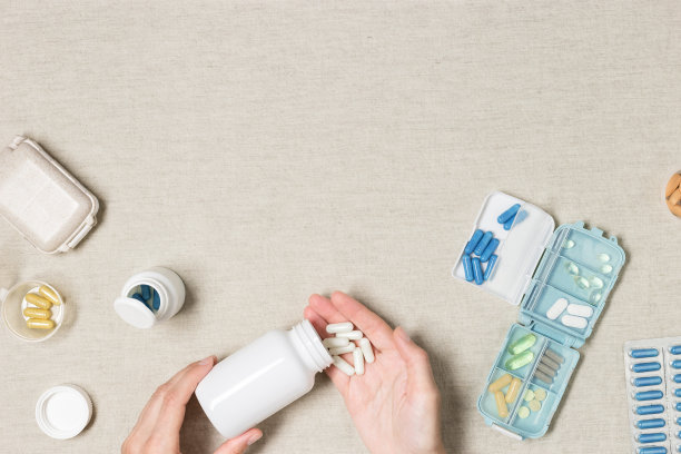 药片盒每日摄入的维生素和药物的布背景。俯视图胶囊和药片在开放的塑料容器在妇女手中。生活方式，美容健康，医疗图片下载