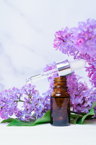 丁香花和精油装在装有吸管的玻璃瓶里，垂直照片图片下载