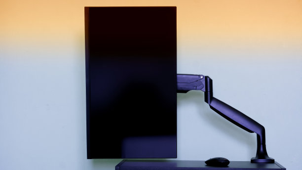 现代的哑光电脑显示器被安装在一个垂直景观位置的小桌子上，使用一个金属支架-一个气动气体升降机。工作场所。为铭文复制空间图片下载