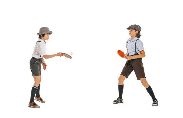 两个学龄男孩，穿着复古服装的时髦孩子在白色背景下打乒乓球。童年观念，爱好图片下载