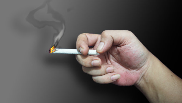 手拿着烟在隔离的颜色背景。图片下载