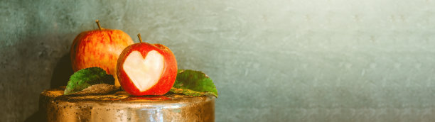 感恩节的秋天背景横幅全景静物——苹果雕刻的心在一个质朴的铜碗，在灰色的混凝土墙前，与复制空间图片下载