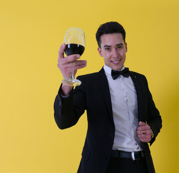 兴高采烈的白人男子穿着西装，打着领结，举起一杯酒图片下载