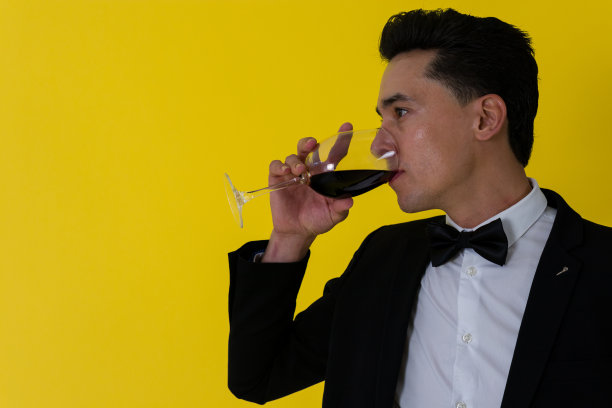 英俊的剃须男子穿着领结西装喝一杯酒图片下载