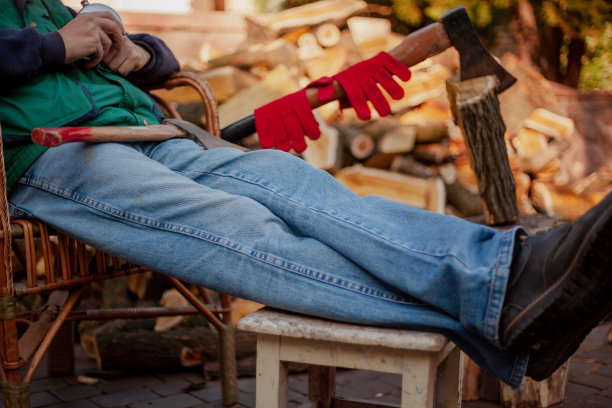 一个男人坐在柴火旁边的椅子上图片下载