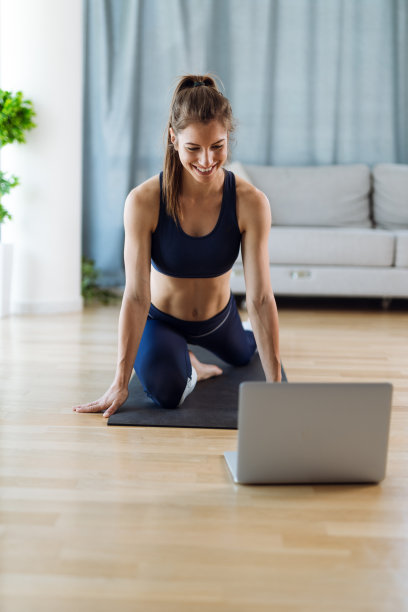 微笑的女人在家锻炼时使用笔记本电脑图片下载