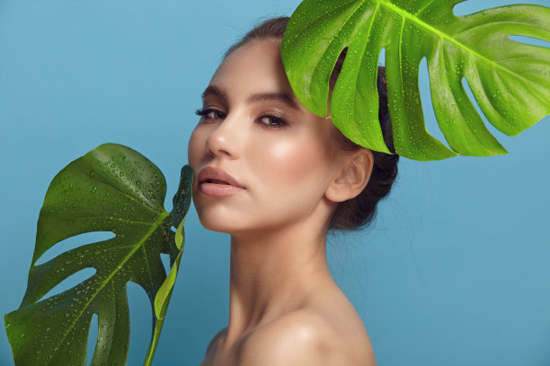 褐色皮肤的女人，憔悴的样子，接近蓝色的棕榈叶图片下载