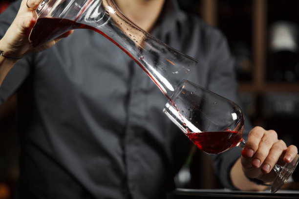 侍酒师将酒从搅拌碗倒入玻璃杯。男服务员图片下载