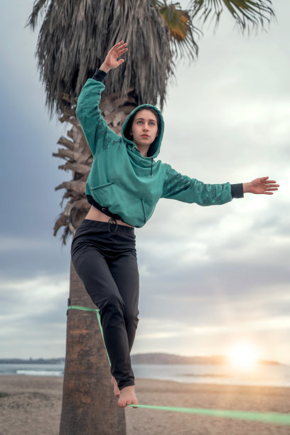 日落时分，拉塞雷娜的海滩上，年轻的拉丁女子在织网、松弛的衬里瑜伽上行走并保持平衡图片下载
