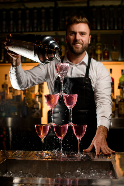 令人惊叹的美丽的塔由玻璃杯制成的调酒师倒入美味的鸡尾酒图片下载