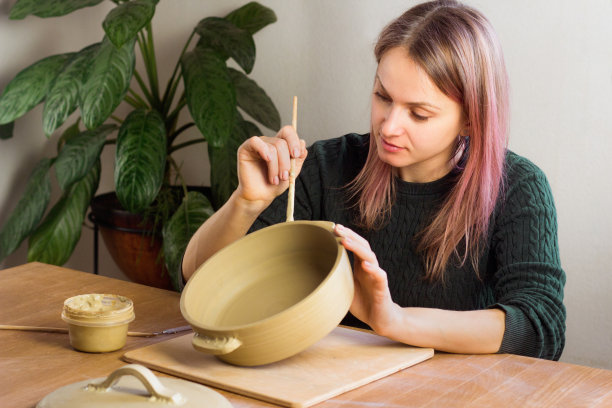 陶艺课上，女陶艺家在锅上安装把手。陶艺工作室的陶工车间图片下载