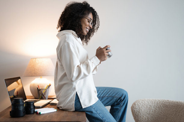 年轻的混合种族女性摄影师与专业相机在办公室图片下载