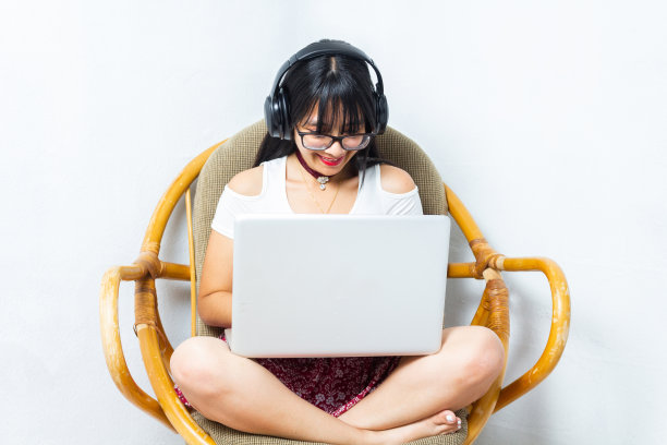 快乐的学生坐在沙发上使用笔记本电脑。在家工作的西班牙裔妇女图片下载