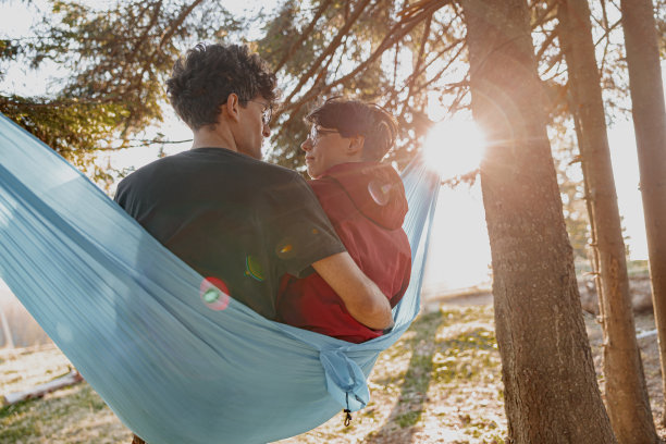 高加索幸福的男人和女人在森林里坐在吊床上拥抱。图片下载