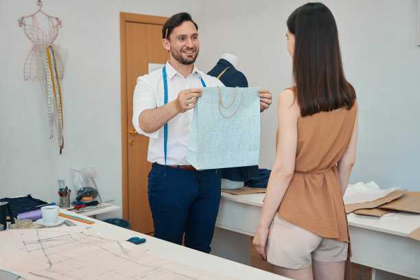 快乐的时装设计师在工作室给年轻的女人发号施令图片下载