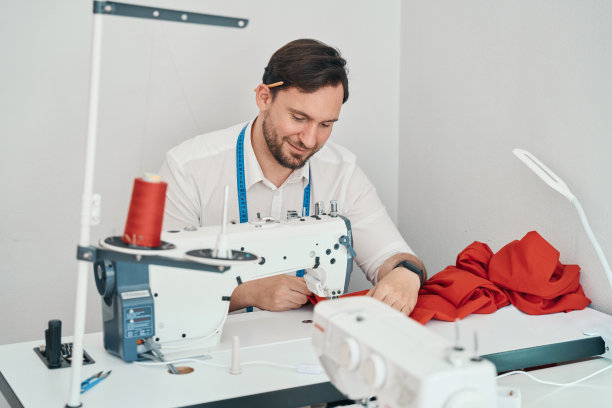 开朗的男裁缝在车间使用缝纫机图片下载
