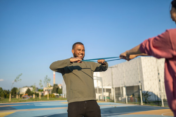 年轻人和她的伴侣在户外用橡皮筋做运动图片下载