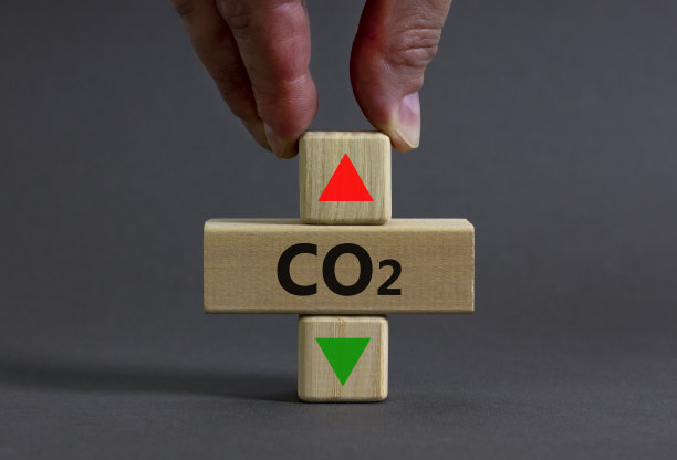 二氧化碳变化的象征。概念词二氧化碳在一个木制的方块上在一个漂亮的灰色桌子灰色的背景上。商人的手。商业、生态和二氧化碳改变观念。副本的空间。图片下载