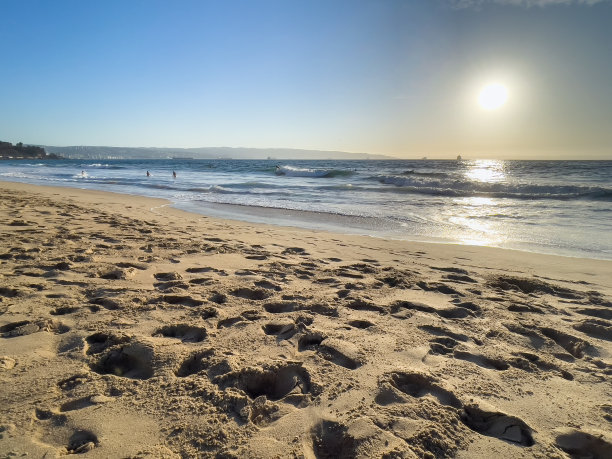 在智利Reñaca海滩，沙滩上的脚印和水面上的人影图片下载