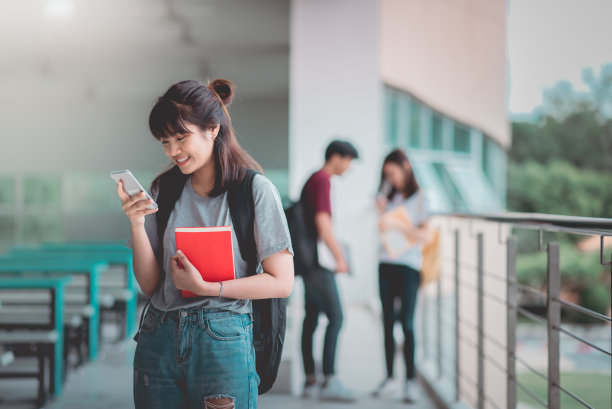 一个亚洲女生站在大学里用智能手机，快乐的教育交流交流。图片下载