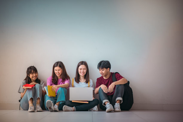 亚洲学生群体使用笔记本电脑、数码平板电脑以及墙上的拷贝空间。生活方式与信息技术小工具教育或社交网络的概念。图片下载