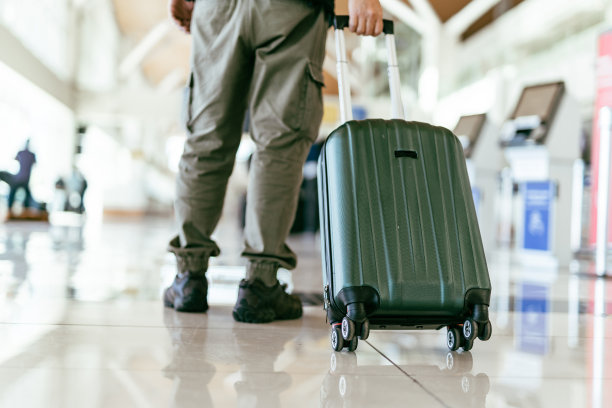 在机场带着轮式行李箱的男子图片下载