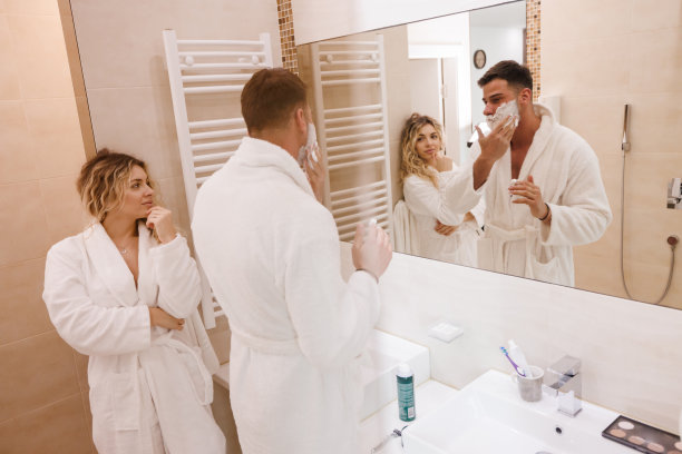 恋爱中的年轻女子看着她的男人在浴室里用剃须泡沫图片下载