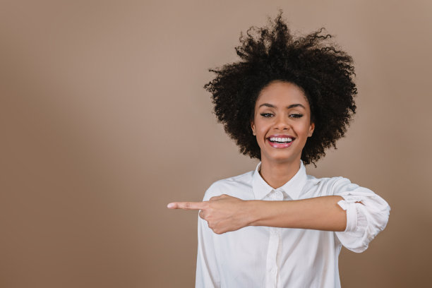 一个年轻的拉丁女孩指着两边。广告和呈现概念。柔和的背景。图片下载