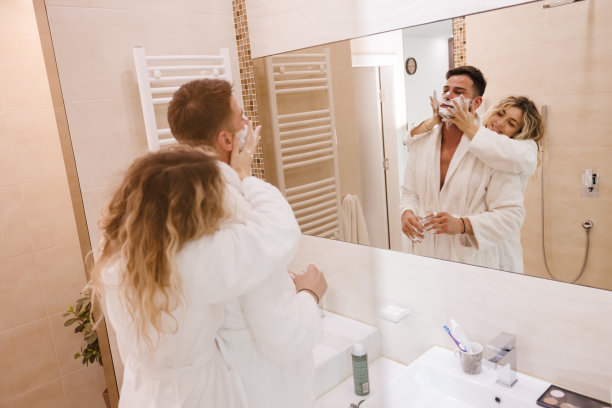 恋爱中的年轻女子看着她的男人在浴室里用剃须泡沫图片下载