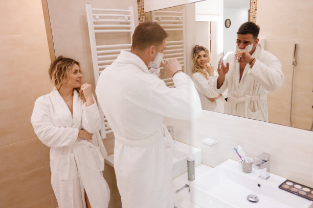 恋爱中的年轻女子看着她的男人在浴室里用剃须泡沫图片下载