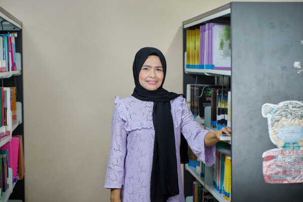 亚洲穆斯林妇女在图书馆的书架上挑选书籍图片下载