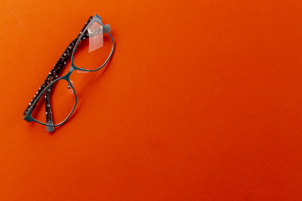 时髦的眼镜在橙色的背景。眼镜选择、验光、验光、时尚配饰概念。俯视图，平铺。图片下载