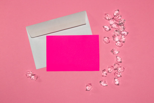字母以粉红色的纸为复印空间，围绕宝石在粉红色的背景上，创意浪漫的艺术设计图片下载