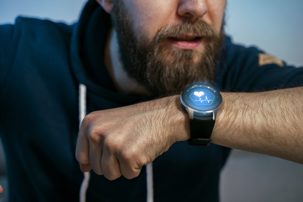 年轻的胡子潮男使用智能手表，健康的心脏符号与心跳在屏幕上图片下载