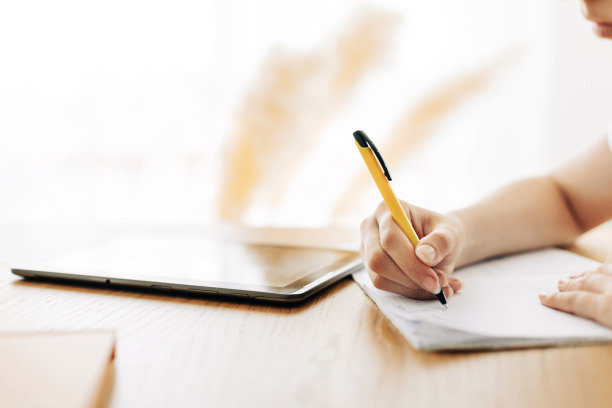 一个正在做作业和在笔记本上写字的女生的手的特写图片下载