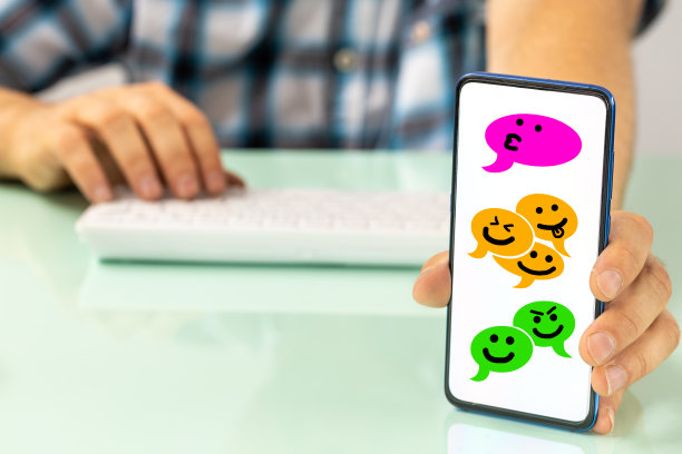 桌子后面的人展示了手机，上面有人们通过社交信息聊天的滑稽对话泡泡，手绘的笑脸，图片下载