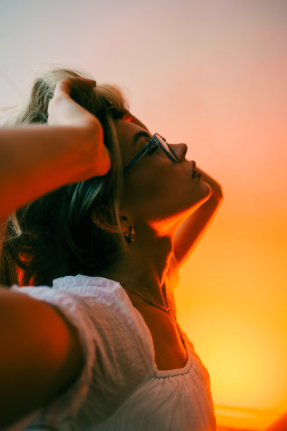 迷人的白人女性时尚模特在眼镜和白色连衣裙的肖像，坐在客厅的地板上与复古装饰。图片下载