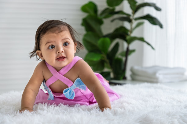 亚洲小女孩在家里的地毯上爬行。新生儿在床上放松。幼儿托儿所。图片下载